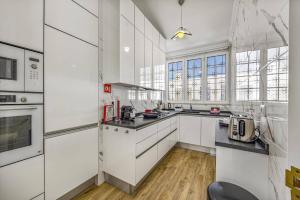 una cucina con mobili bianchi e una grande finestra di Villa Medicis by Villa Plus a Vale de Pedras