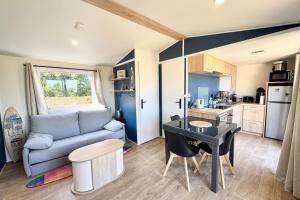 une cuisine et un salon avec un canapé et une table dans l'établissement Bungalow & caravane vintage proche plages, à Ploemeur