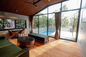 a living room with a large window and a pool at Forrest in Mahabalipuram