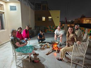 a group of people sitting in chairs around a fire at The Pink Nest - Backpackers Abode in Jaipur