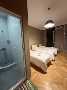 a room with three beds and a shower and a glass door at Nest Stay in Tbilisi City
