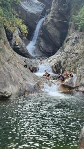 a group of people swimming in a river with a waterfall at Thac so 6 homestay in Ha Giang