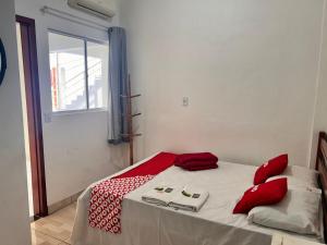 a bedroom with a bed with red pillows and a window at OYO Pousada Paraná, Cuiabá in Cuiabá