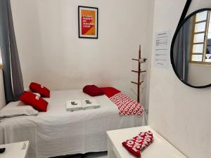 a room with a bed with red pillows and a mirror at OYO Pousada Paraná, Cuiabá in Cuiabá