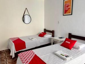 two beds in a room with red and white pillows at OYO Pousada Paraná, Cuiabá in Cuiabá +43 photos