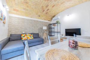Una sala de estar con un sofá azul y un televisor. en Il rifugio delle Azalee, en Roma