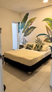 a bedroom with a bed with a mural on the wall at Baku Laureles Hostel in Medellín