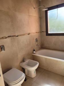 a bathroom with a toilet and a tub and a sink at Sierras de Córdoba Ascochinga in La Pampa
