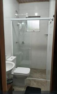 a bathroom with a toilet and a glass shower at Suíte Cambury in São Sebastião