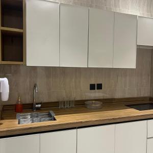 a kitchen with white cabinets and a wooden counter top at شقق ضيافة البرج in Al Kharj