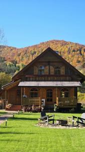a large wooden house with a hill in the background at Bieszczadzki Rewir in Wetlina