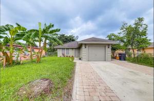 a house with a garage in a yard at Downtown Lake Worth Retreat in Lake Worth Corridor