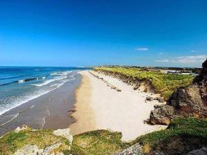 a sandy beach with the ocean and a blue sky at Aurora Sky in Lossiemouth