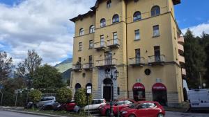 a yellow building with cars parked in front of it at Roccolo apartment in Pieve di Cadore