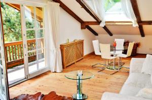 uma sala de estar com uma mesa, cadeiras e janelas em Chiemsee Landhaus em Breitbrunn am Chiemsee