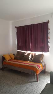 Bett in einem Zimmer mit einem roten Vorhang in der Unterkunft Casa con jardín y vista al cerro en Portezuelo Salta in Salta