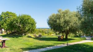 a park with benches and tables and trees at HOTEL Essenza di Mirto in La Caletta