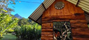 a clock on the side of a wooden building at Sapiens house la cabaña del Reloj in Cali