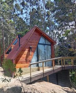 a cabin in the woods with a wooden deck at Vale Aurora Cabanas in Tijucas