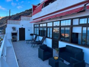 een huis met een patio met stoelen en een balkon bij Crisol Apartamento in Puerto de la Madera