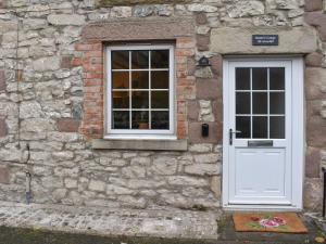 a stone building with a white door and a window at Stone Cottage in Wirksworth near Peak District in Wirksworth +5 photos