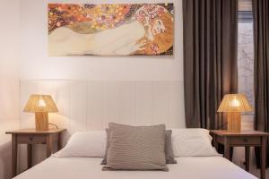 Un dormitorio con una cama con dos lámparas y un cuadro. en Portal Del Angel Barcelona Apartment, en Barcelona
