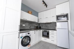 a kitchen with white cabinets and a washer and dryer at Apart house EMA 2 in Bansko +7 photos