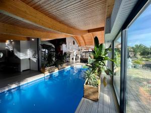 a swimming pool in a house with a wooden ceiling at Villa du Siéck bord de mer piscine 14 P in Santec