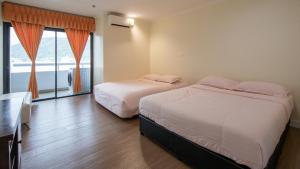 two beds in a hotel room with a window at PATONG TOWER SPACIOUS FAMILIES APARTMENT with 2 BATHROOMS 3&4 BEDROOMS Pta in Patong Beach +20 photos