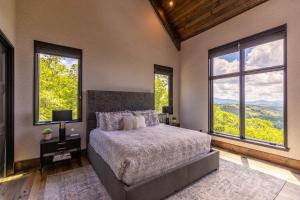 a bedroom with a large bed and large windows at Bucks and Bunnies at Eagles Nest in Elk Park
