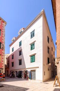 a large white building with green windows on a street at Apartments Palace Rialto in Šibenik