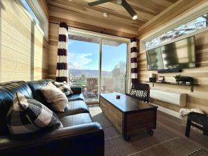 a living room with a leather couch and a flat screen tv at Escalante Escapes Tumble Weed- Bunk Escape in Escalante