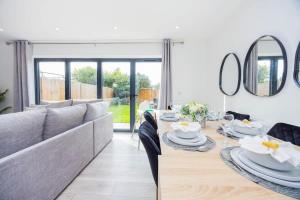 een woonkamer met een bank en een tafel met borden erop bij New 3 Bed House, Sittingbourne, Sleeps 7, Contractors, Families , Weekly and Monthly Offers in Milton Regis