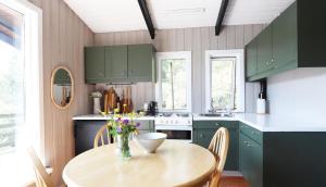 een keuken met groene kasten en een houten tafel bij Cosy Cabin Escape with Hot Tub & Lake View in Lundur +4 foto's