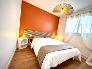 une chambre avec un grand lit avec un mur orange dans l'établissement La bohème du clocher - Cosy calme hyper-centre 2 à 6 pers, à Bergerac