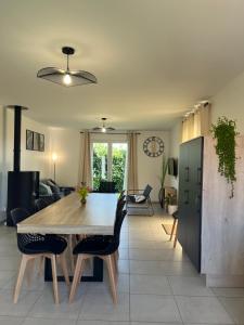 a dining table and chairs in a living room at Gîte neuf, à 12mn du Futuroscope, à la campagne -Le Trèfle in Saint-Léger