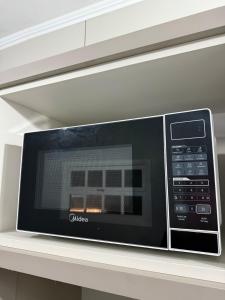 a microwave oven sitting on top of a shelf at Apartamento pé na areia em Tramandaí in Tramandaí