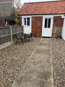 a patio with two chairs and a table in front of a house at Holly cottage in Catfield +3 photos