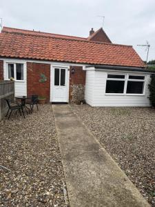 a house with a patio and a table in front of it at Holly cottage in Catfield