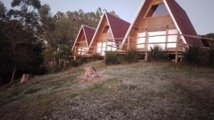 a large wooden house on a grassy hill at CascataDiamantePousada in Laurentino