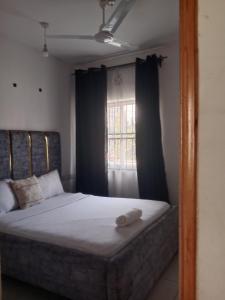 a bedroom with a bed and a window with curtains at Buxton Point Kandy Cozy Two Bedroom Apartment in Mombasa