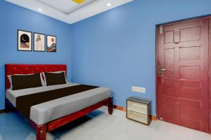 a bedroom with a bed and a red door at Hotel O Redmoon Chikkamagaluru Railway Station in Chikmagalūr
