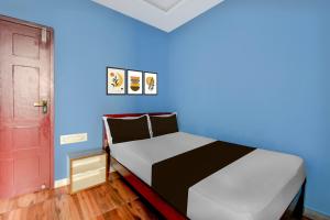 a bed in a room with a blue wall at Hotel O Redmoon Chikkamagaluru Railway Station in Chikmagalūr