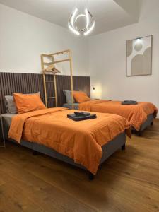 two beds with orange sheets in a room at Work and Chill Apartment near Zermatt and Lonza in Stalden