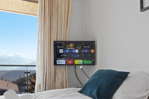 a flat screen tv hanging on a wall in a bedroom at Crans-Montana, 5 pers, balcon vue et parking privé in Crans-Montana
