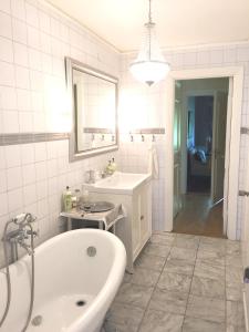 a white bathroom with a tub and a sink at Villa Granvik in Söderfors