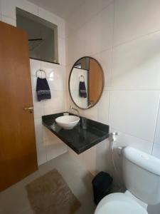 a bathroom with a sink and a mirror and a toilet at Sol Nascente Apartamento in Ilhéus