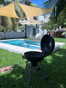 una parrilla sentada en el césped junto a una piscina en BuenaMar Malibu Beach, en Sonsonate