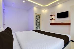 a bedroom with a white bed and a tv on the wall at Hotel O Acroview in Ballygunge