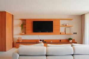 un salon avec deux canapés blancs et une télévision dans l'établissement Casa Pé na Areia | Rooftop, 5 suítes, piscina, à Barra do Camaragibe